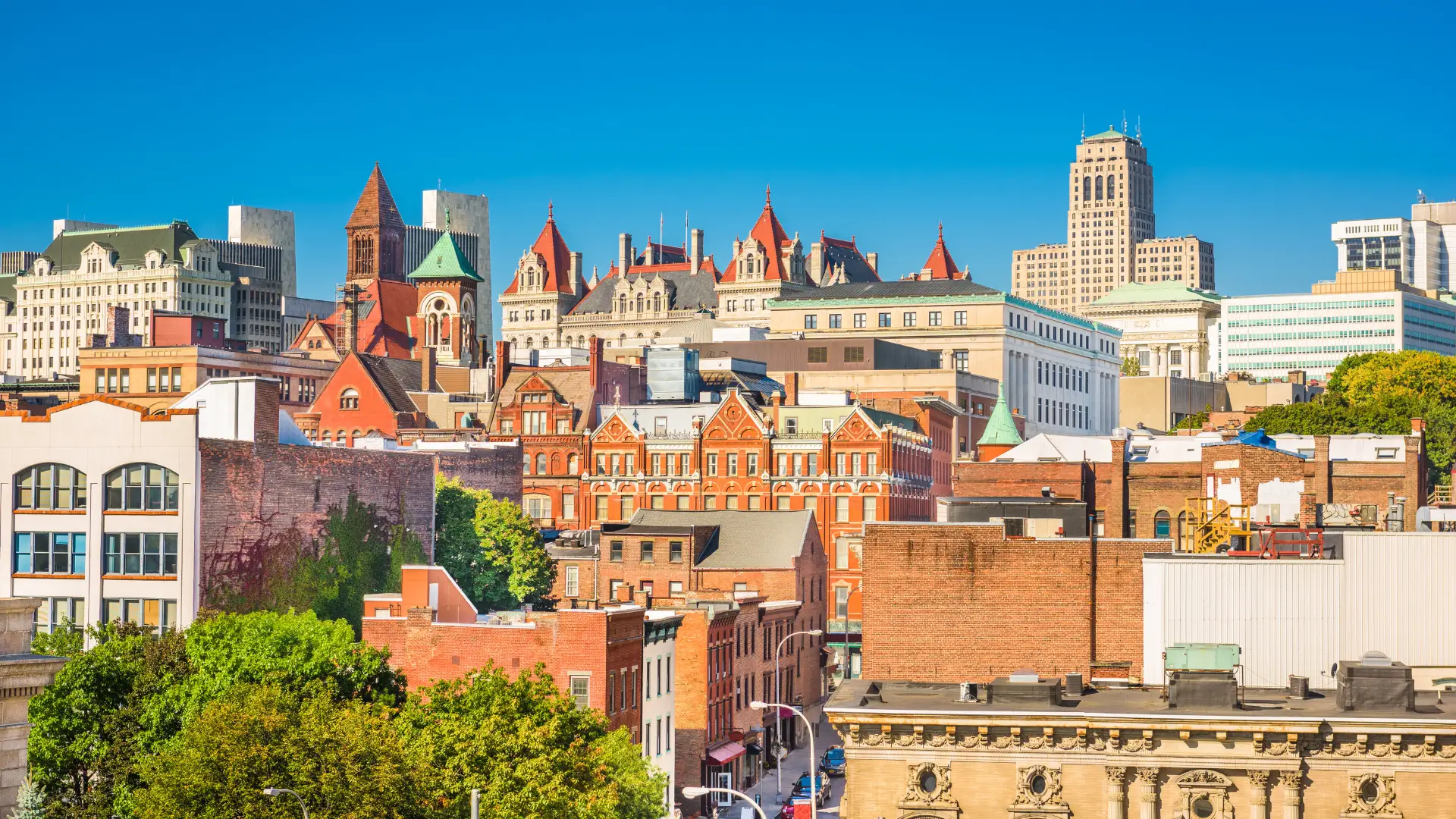 Scenic view of Albany, NY with urban buildings, tree-lined roads, and classic Northeast city atmosphere near the Hudson River.
