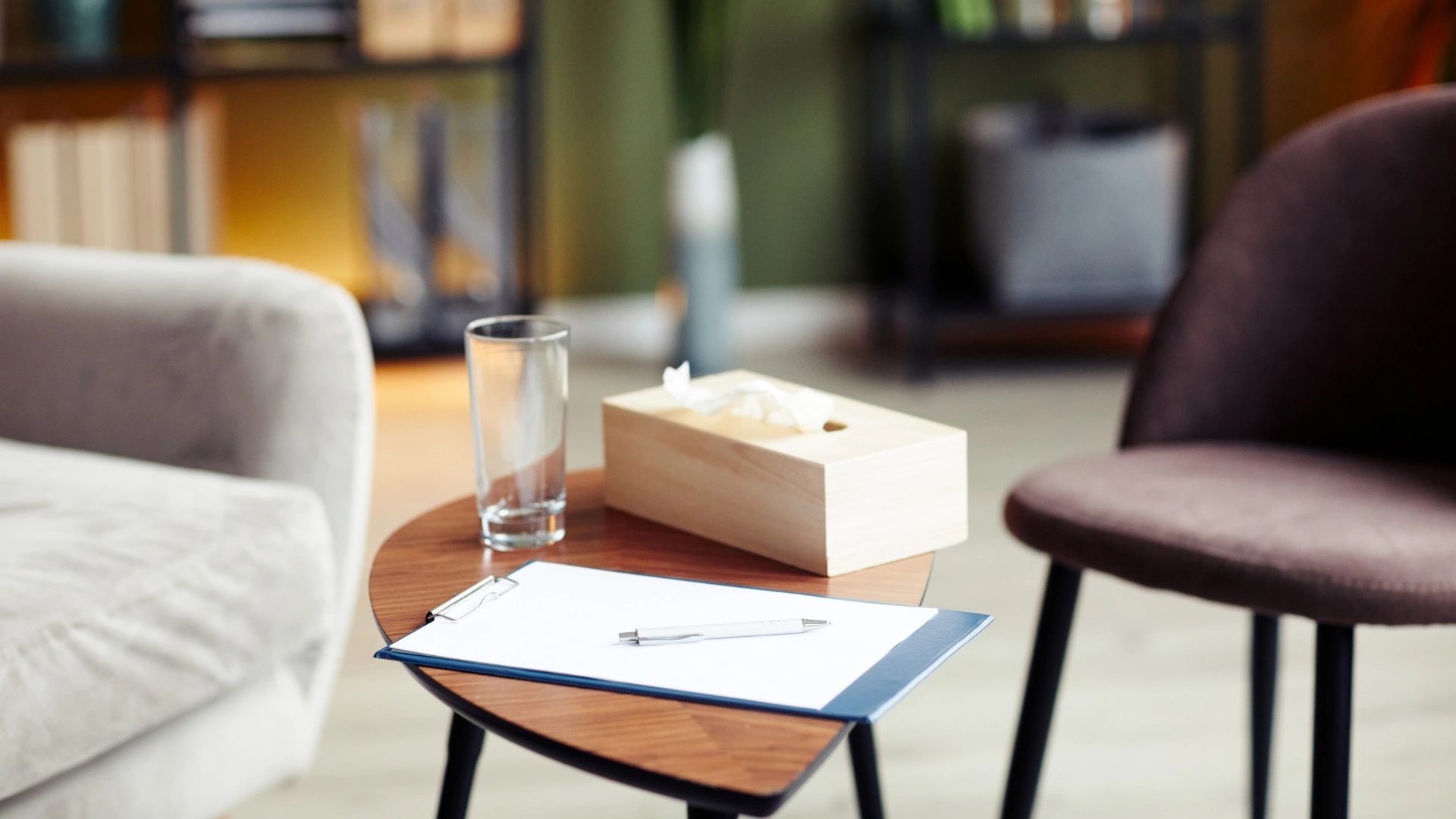 A notepad and pen placed on a wooden table in a cozy living room setting.