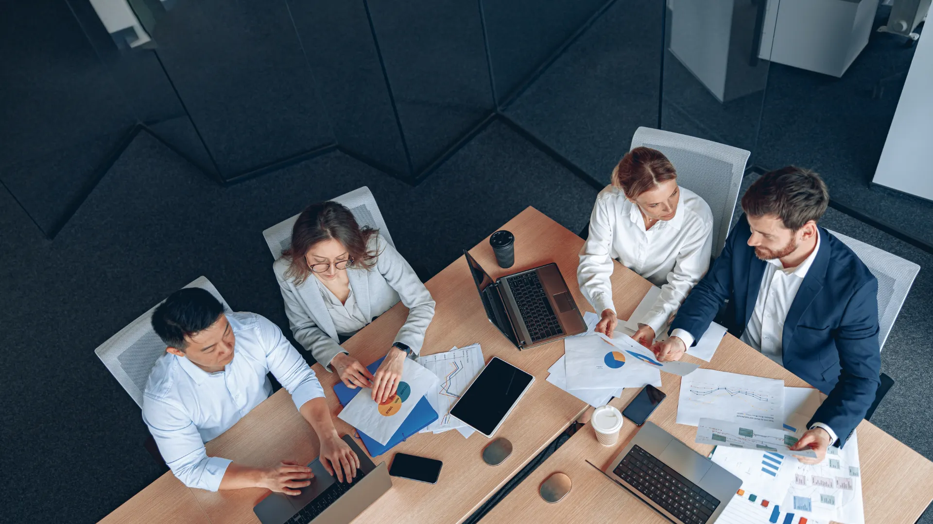 A group of business professionals collaborating around a conference table, engaged in discussion and reviewing documents.